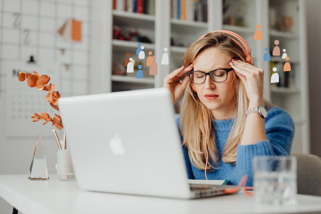 A woman feeling stressed while working from home using a laptop, wearing headphones.