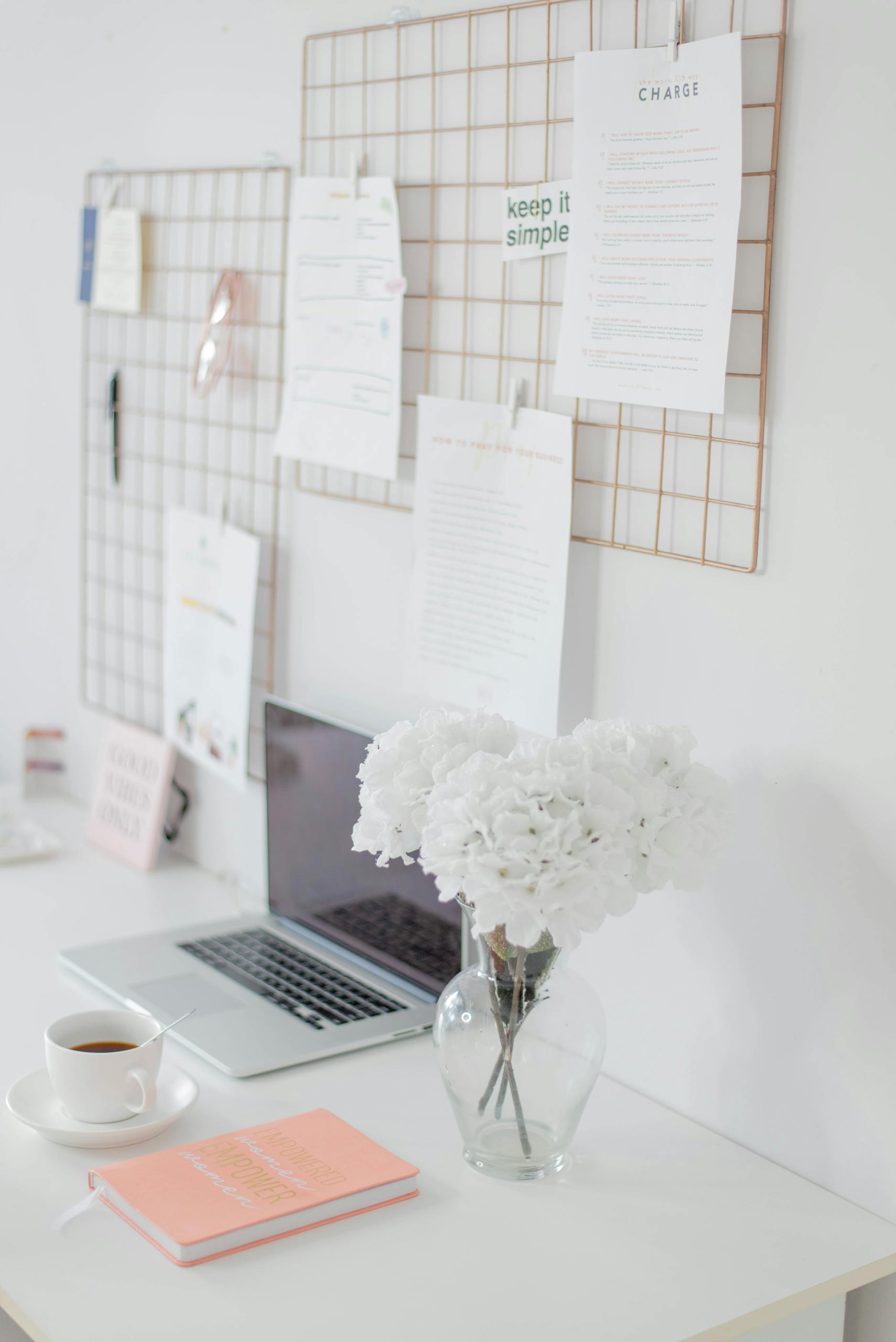 Clean and modern home office setup with flowers, a laptop, and organized decor.